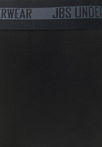 Černé spodní prádlo s hladkým povrchem a šedým elastickým pasem embosovaným textem "JBS UNDERWEAR" tmavým písmem.