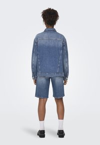 Conjunto de chaqueta de mezclilla y pantalones cortos en azul claro, con un corte clásico, detalles de botones y costuras visibles. Textura suave, diseño casual.