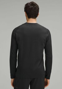 Czarny longsleeve z teksturowanej tkaniny, z okrągłym dekoltem i rękawami raglanowymi. Gładki materiał i prosty design.