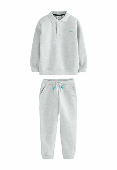 Pilkas medvilnės džemperis su apykakle ir ilgomis rankovėmis, derinamas su atitinkamomis džinsinėmis kelnėmis, turinčiomis šonines kišenes ir raištelių juosmeniu.