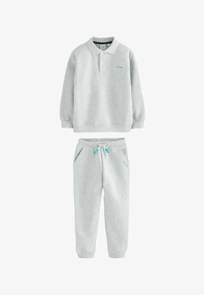 Pilkas medvilnės džemperis su apykakle ir ilgomis rankovėmis, derinamas su atitinkamomis džinsinėmis kelnėmis, turinčiomis šonines kišenes ir raištelių juosmeniu.