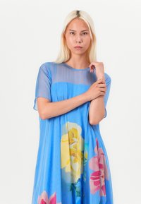 Light blue floral dress with short sleeves, made of soft fabric, featuring large yellow and pink flower prints on the front.