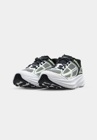 Black and white running shoes with a mesh upper, neon green accents, and textured soles for grip. Features intricate lacing design.