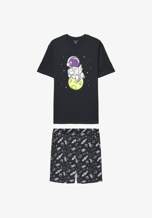Maglietta nera in cotone con grafica colorata di un astronauta, abbinata a pantaloncini neri con motivi spaziali bianchi e vita elastica.
