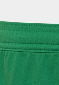 Groene stof met een gladde structuur, voorzien van een brede elastische tailleband en platte stiksels. Het materiaal lijkt zacht en rekbaar.