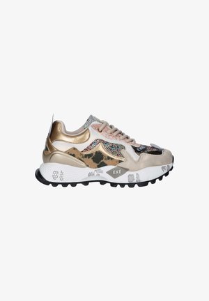 Zapatilla chunky con paneles en dorado, beige y estampado de leopardo, piedras de strass multicolor, suela blanca con dibujo negro y marca "EXÉ" en el lateral.