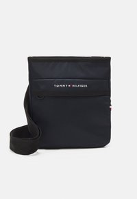 Námořnická obdélníková crossbody taška vyrobená z nylonu, s klopovým uzávěrem, nastavitelným popruhem a bílým nápisem loga s červenými a modrými akcenty.