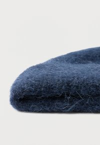 Căciulă de lână bleumarin cu un finisaj moale și texturat, având un tiv pliat și o formă ușor rotunjită în partea de sus.