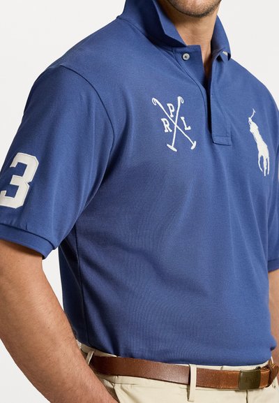 Polo de culoare albastră cu guler, având accente brodate albe: un număr 3 pe mânecă și un logo cu jucător de polo pe piept.