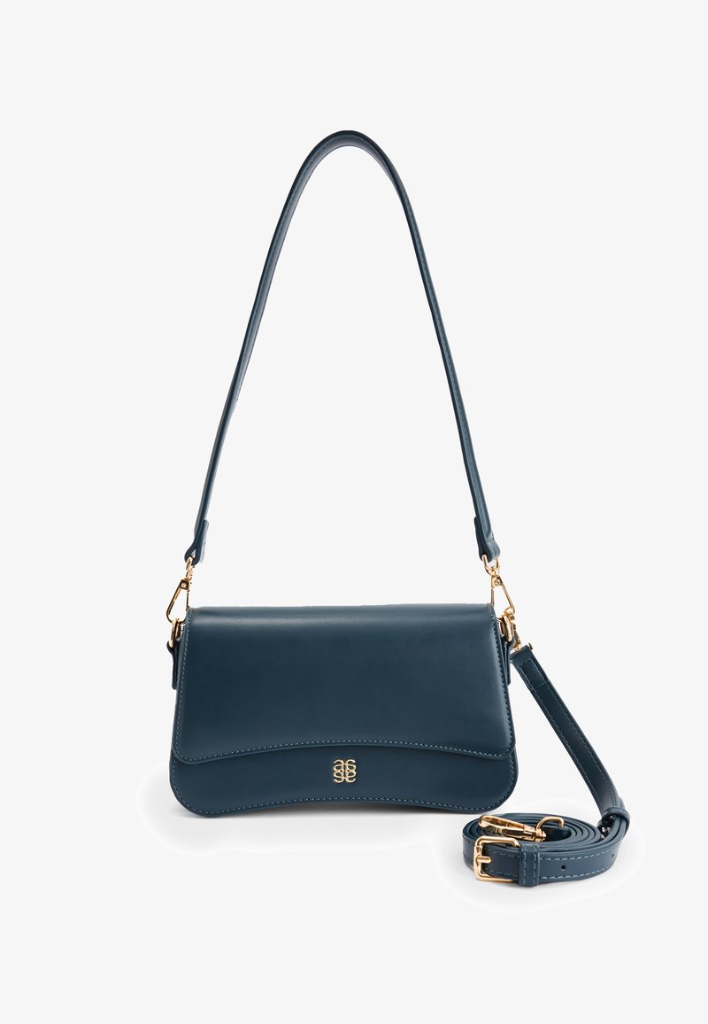 Sininen nahkainen käsilaukku, jossa on kaareva läppä ja kultaiset yksityiskohdat. Varustettu irrotettavalla hihnalla ja sileällä pinnalla, joka tarjoaa tyylikkään muotoilun.