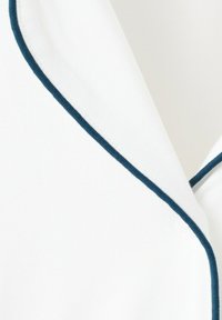 Tissu blanc avec un liseré bleu foncé le long d'un bord plié, ressemblant à une partie d'un col ou revers de vêtement.