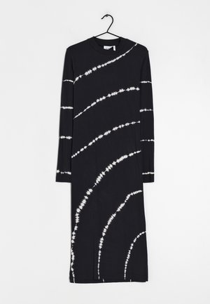 Robe midi noire à manches longues avec des rayures diagonales blanches tie-dye, col rond, suspendue sur un cintre noir sur fond blanc.