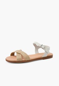 Sandały na płaskiej brązowej podeszwie z plecionym górnym częścią z naturalnego włókna, białymi skórzanymi akcentami i regulowanym paskiem wokół kostki.