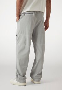 Light gray cargo trousers with a relaxed fit. Features side pockets, a zippered back pocket, and a smooth, soft texture.