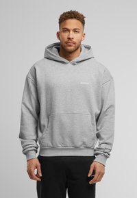 Grijze hoodie gemaakt van zacht stof. Voorzien van een voorzak en geribde manchetten en onderkant. Merkl logo gedrukt op de borst.