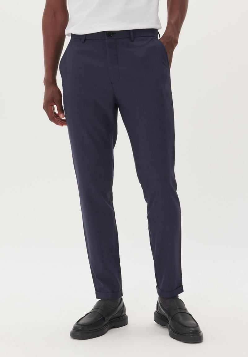 Pantaloni a quadri blu navy con una vestibilità su misura, frontale piatto e tasche laterali; abbinati a scarpe in pelle nere per un aspetto raffinato.