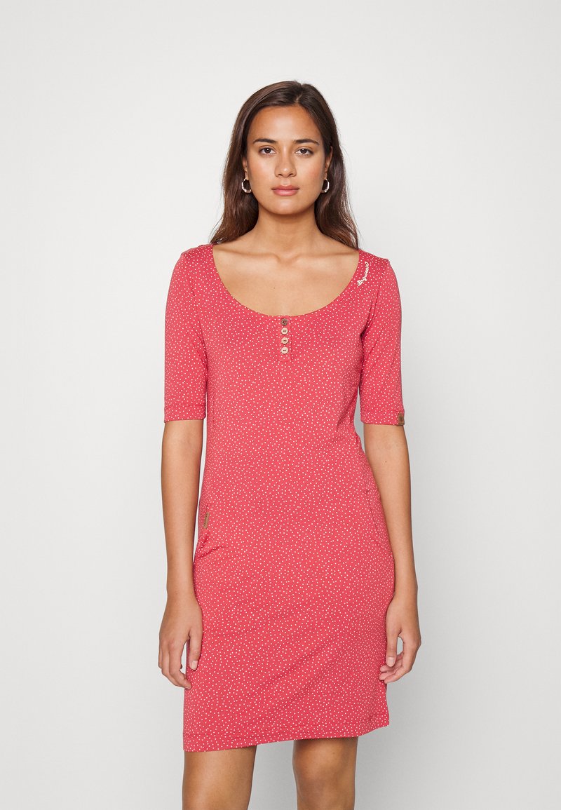 Vestido de manga curta em coral com bolinhas brancas, apresentando um decote redondo, três botões e um bolso lateral. Tecido suave e elástico.