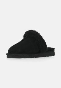Sorte fuzzy hjemmesko lavet af blødt ruskind med en plyssede pelskant. Har en flad sål og et åbent design for nem påtagning.
