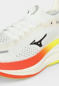 Λευκό παπούτσι τρεξίματος Mizuno με πορτοκαλί και κίτρινη βαθμιδωτή σόλα και μαύρο λογότυπο στο πλάι, που δείχνει λεπτομερή υφή πλεξίματος και κορδόνια.