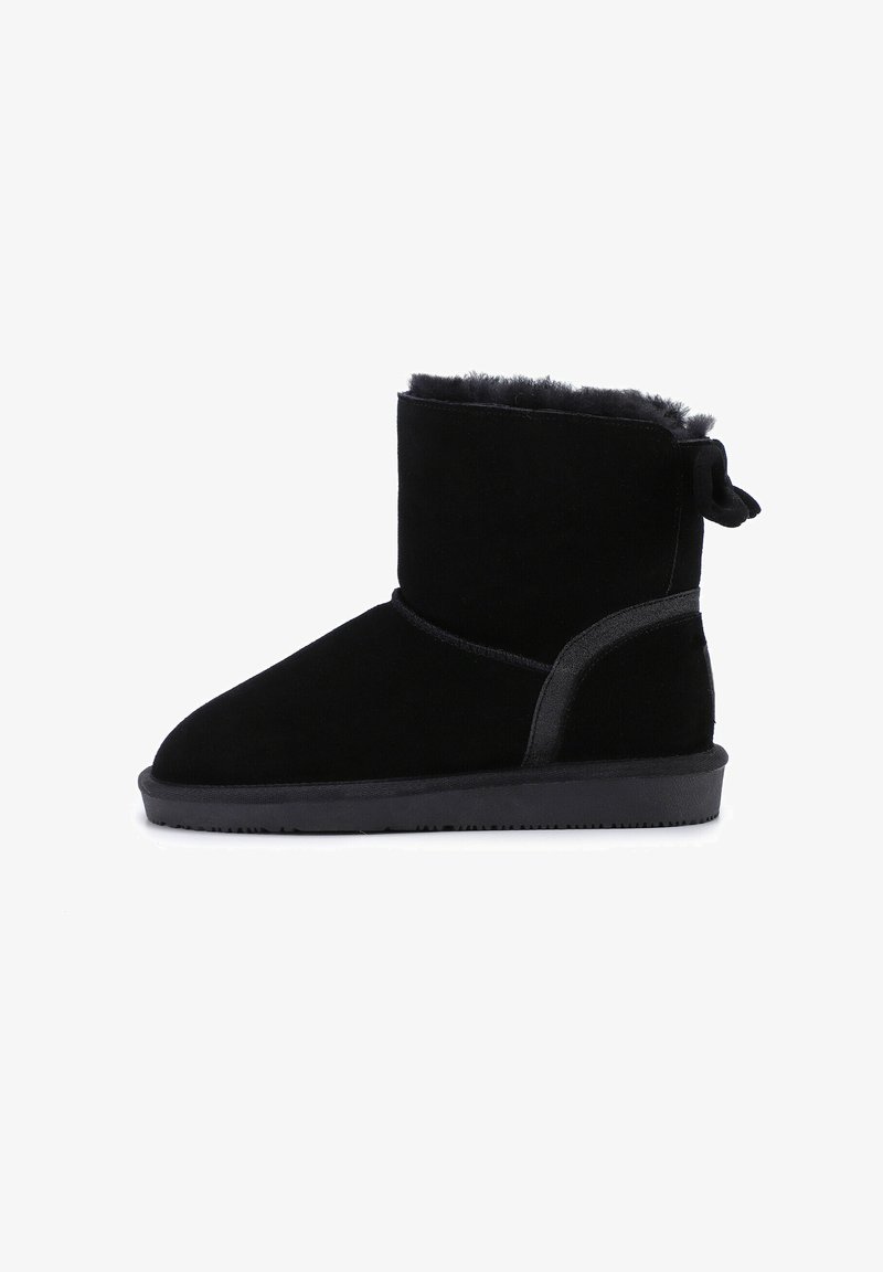 Botines negros de ante suave, con un interior acolchado, suela de goma y un detalle de lazo decorativo en la parte trasera.
