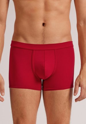 Rote, enganliegende Boxershorts mit mittelhohem Bund, aus glattem Material gefertigt, mit einem Vorderfach und kontrastierenden Nahtdetails.