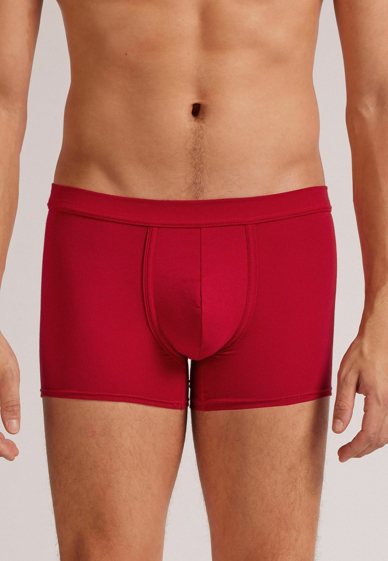 Boxers rojos ajustados con una cinturilla de altura media, hechos de tela suave, que cuentan con un bolsillo delantero y costuras de contraste.