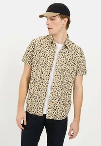 Kurzarm-Hemd mit Knöpfen in einem geometrischen Muster aus Beige, Schwarz und Braun; leichtes Material und kragenförmiges Design.