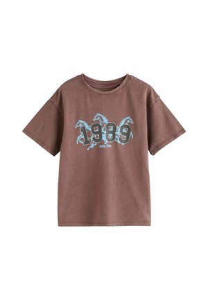 Braunes kurzärmeliges T-Shirt mit blau umrandeten Pferden und großem "1989"-Text sowie kleinerem "Austin, Texas"-Text unter den Zahlen.