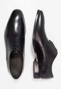 Chaussures habillées en cuir noir avec un design élégant, bout pointu, surface lisse et détails de couture subtils le long du cou-de-pied.