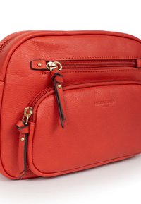 Borsa rossa in pelle con una superficie liscia, dotata di una tasca frontale con zip, accessori in metallo dorato e dettagli in nero sui tiranti della zip.