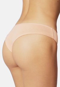 Undergarment di colore pesca realizzato in tessuto morbido, con design senza cuciture, vita bassa e bordi lisci.