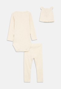 Σετ ρούχων μωρού τριών τεμαχίων σε μπεζ χρώμα, που περιλαμβάνει κορμάκι με μακριά μανίκια, κολάν και καπέλο με αυτιά αρκούδας. Κατασκευασμένο από μαλακό, υφασμάτινο υλικό με υφή.