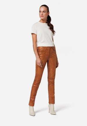 Tan leather pants with fitted design and subtle side pockets, paired with a plain white crew-neck t-shirt and beige heels.