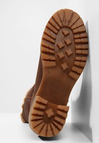 Suela de bota de goma marrón con patrón de relieve texturizado, que presenta agarres hexagonales y rectangulares elevados para mayor tracción. Talla 37 visible.