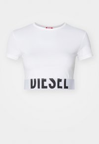 T-shirt court blanc en coton lisse, avec une bande logo "DIESEL" noire à l'ourlet et un col rond classique. Manches courtes.