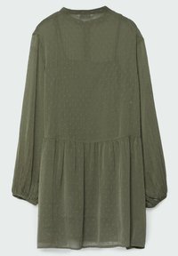 Grünes, langärmliges Kleid aus transparenter Stoff mit gerafftem Taillenbereich und strukturiertem Punktemuster. Rundhalsausschnitt und luftige Ärmel.