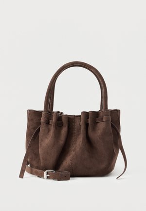 Ruda zomšinė rankinė su surinktu viršumi, dvigubomis rankenomis ir nuimama dirželio sagtimi sidabrine sagtimi, eksponuojama priešais paprastą foną.