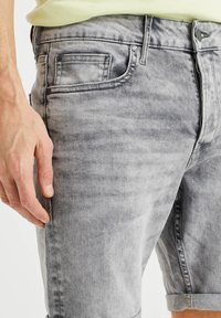 Grå denimshorts med en urtvättad look, femficksdesign och uppvikta ärmslut. Har dragkedja och metallhardwaredetaljer.