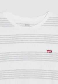 Bílý bavlněný tričko s světle šedými vodorovnými pruhy, s kulatým výstřihem a červeným logem Levi's na levé části hrudi.