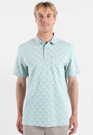 Polo à manches courtes bleu clair avec un motif d'arbre subtil. Présente une patte de boutonnage et une poche poitrine. Texture de tissu lisse.