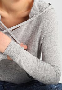 Felpa a maniche lunghe grigio chiaro, realizzata in un morbido tessuto testurizzato. Presenta un collo aperto incrociato e polsini aderenti. Design casual.