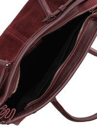 Borsa a mano in pelle bordeaux con texture in camoscio e liscia, tasche interne con zip e cuciture rosse a contrasto. Vista aperta che mostra la fodera.