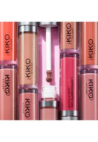 Assortimento di rossetti liquidi KIKO Milano in diverse tonalità di nude, rosa e corallo, con un applicatore esposto su uno sfondo rosa.