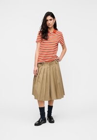 Κόκκινη και λευκή ριγέ πόλο μπλούζα, μπεζ πλισέ φούστα, ναυτικά καλτσάκια και μαύρα παπούτσια. Η εμφάνιση χαρακτηρίζεται από ένα χαλαρό και άνετο σχέδιο.