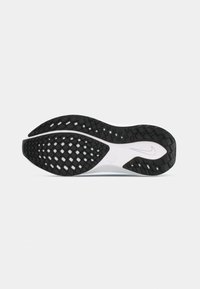 Semelle de chaussure de sport en noir et blanc avec un motif de grip texturé et des designs ressemblant à des diamants, arborant un logo central et une forme arrondie.