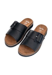 Black leather slide sandals with a wide strap, decorative buckle, brown suede insole, and a textured rubber outsole.