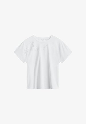 Hvid T-shirt med korte ærmer og diskret blomsterblondeudskæring på øverste venstre side nær skulderen.