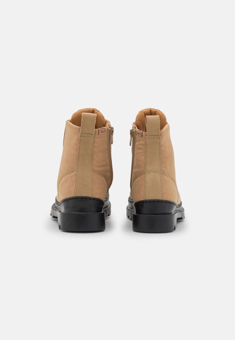 Helle Leder-Stiefeletten mit schwarzen Gummisohlen, doppelten seitlichen Reißverschlüssen und einer strukturierten Oberfläche. Verfügt über ein weiches Innenfutter und verstärkte Nähte.