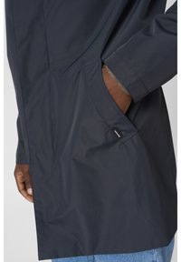 Navy waterproof jacket with a streamlined design, featuring a side pocket, elastic cuffs, and a smooth texture. Visible logo detail.