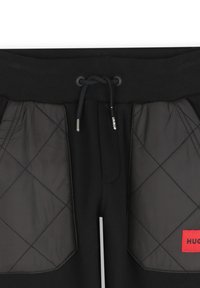 Zwarte joggers met geribde tailleband en trekkoord, voorzien van diamantgequilte zwarte stof zijdelen en een rode logopatch.